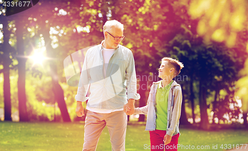 Image of grandfather and grandson walking at summer park