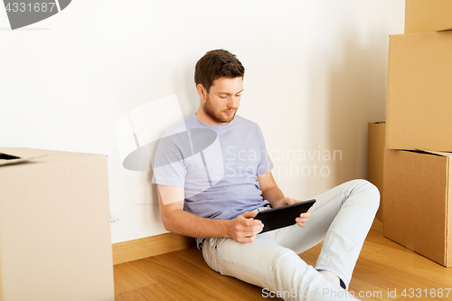 Image of man with tablet pc and boxes moving to new home