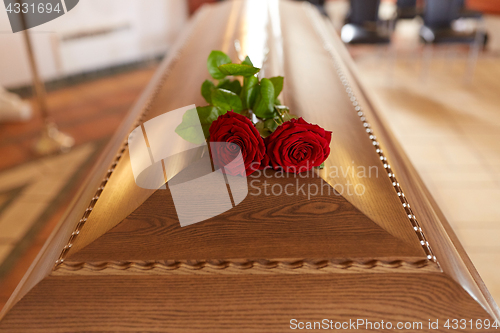 Image of red rose flowers on wooden coffin in church