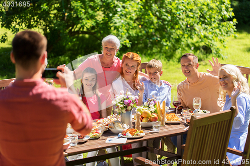 Image of happy family photographing by smartphone in summer