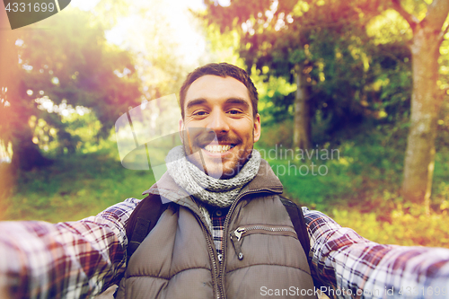 Image of happy man with backpack taking selfie and hiking
