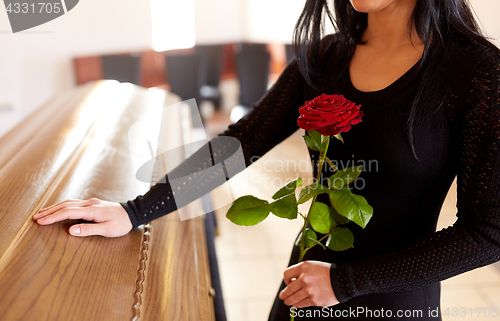 Image of woman with red roses and coffin at funeral