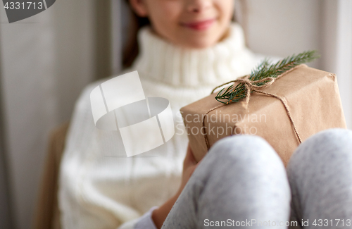 Image of girl with christmas gift sitting on sill at home