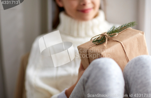 Image of girl with christmas gift sitting on sill at home