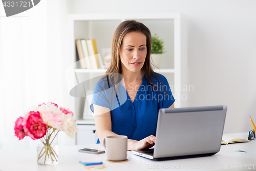 Image of happy woman with laptop working at home or office