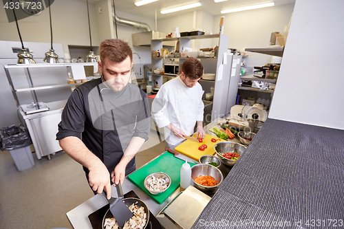 Image of chef and cook cooking food at restaurant kitchen