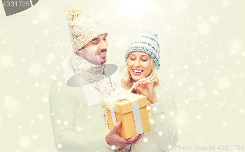 Image of smiling couple in winter clothes with gift box