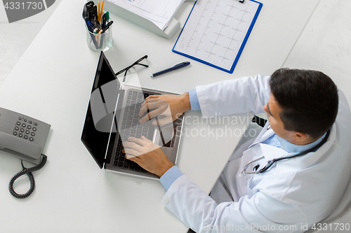 Image of doctor with cardiogram and laptop at clinic