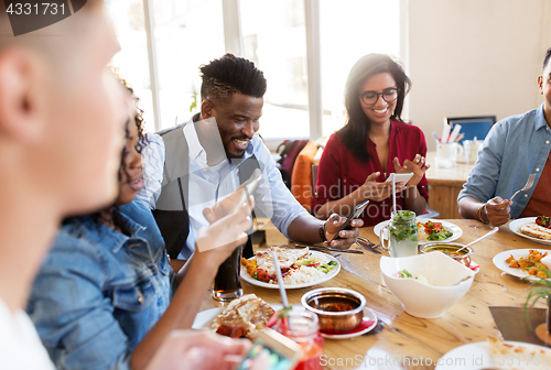 Image of happy friends with smartphones at restaurant