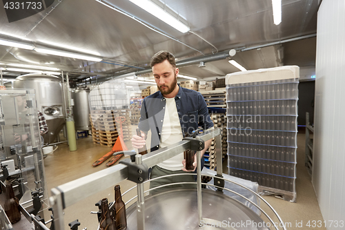 Image of men with bottles on conveyor at craft beer brewery