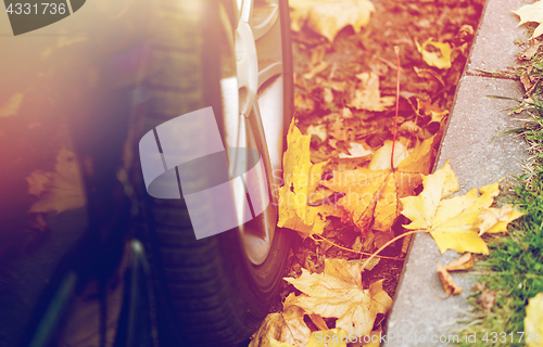 Image of close up of car wheel and autumn leaves