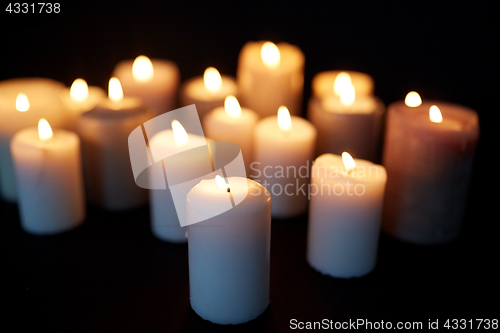 Image of candles burning in darkness over black background