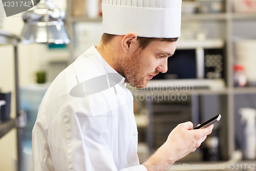 Image of close up of chef with smartphone at kitchen