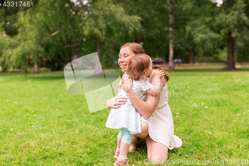 Image of happy mother hugging baby girl at summer park