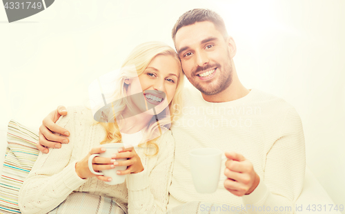 Image of happy couple with cups drinking tea at home