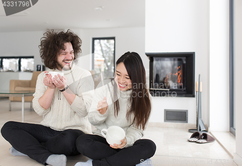 Image of happy multiethnic couple  in front of fireplace