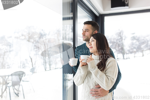 Image of multiethnic couple enjoying morning coffee by the window