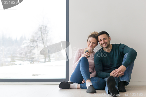 Image of young couple sitting on the floor near window at home