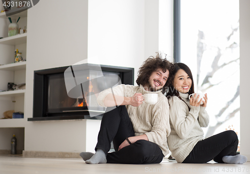 Image of happy multiethnic couple  in front of fireplace