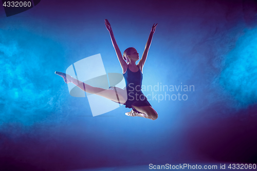 Image of Beautiful young ballet dancer jumping on a lilac background.