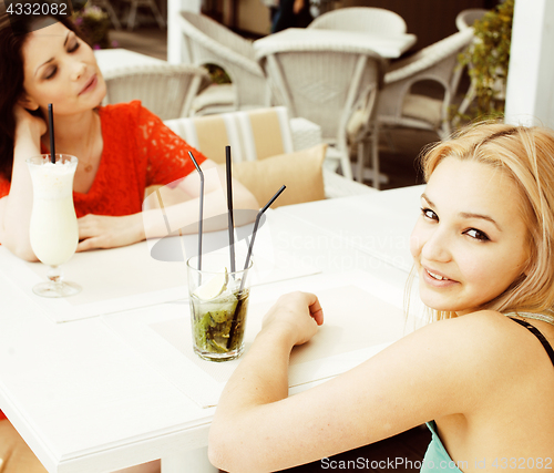 Image of portrait of two pretty friends in cafe drinking and talking