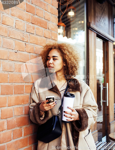 Image of young pretty african american women drinking coffee outside in c