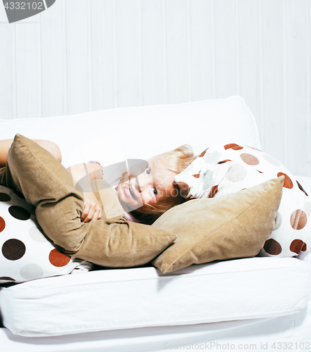 Image of little cute blonde girl playing at home with pillows