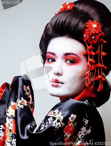 Image of young pretty geisha in black kimono among sakura, asian ethno close up