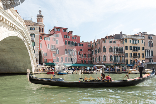 Image of Famous Ponte di Rialto with traditional gondola passing in Venice, Italy