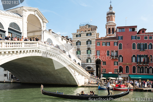 Image of Famous Ponte di Rialto with traditional gondola passing in Venice, Italy
