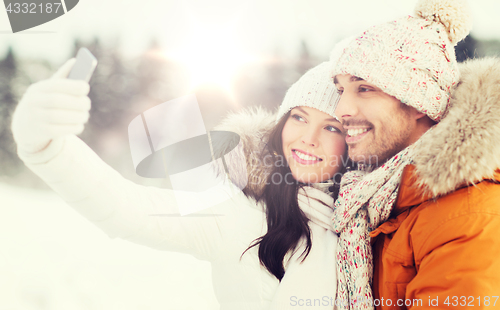 Image of happy couple taking selfie by smartphone in winter