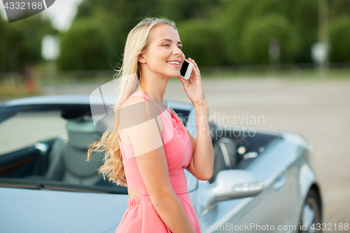 Image of woman calling on smartphone at convertible car