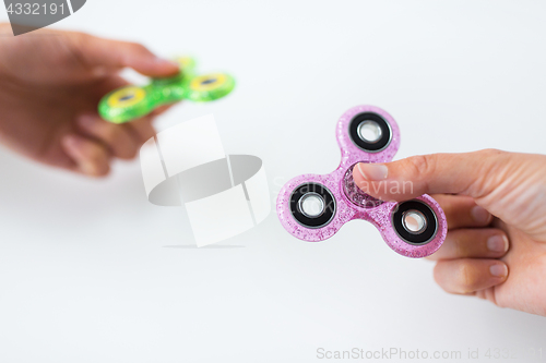 Image of close up of two hands playing with fidget spinners