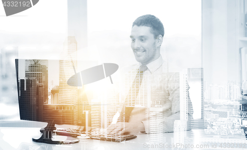 Image of smiling businessman with computer at office