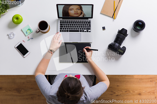 Image of woman with camera working on laptop at table