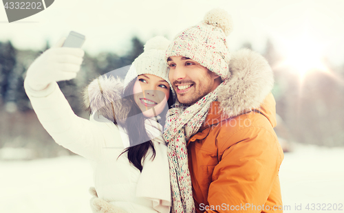 Image of happy couple taking selfie by smartphone in winter