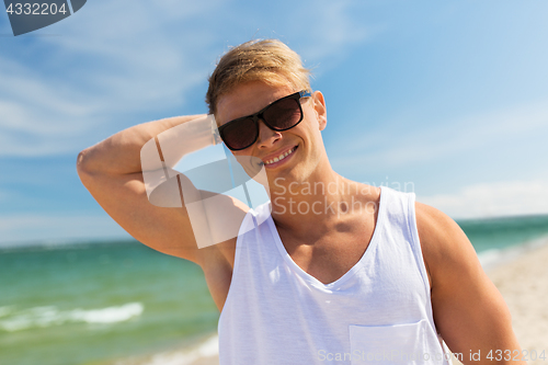 Image of smiling young man in sunglasses on summer beach