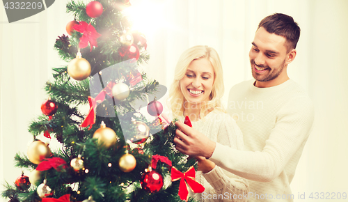 Image of happy couple decorating christmas tree at home