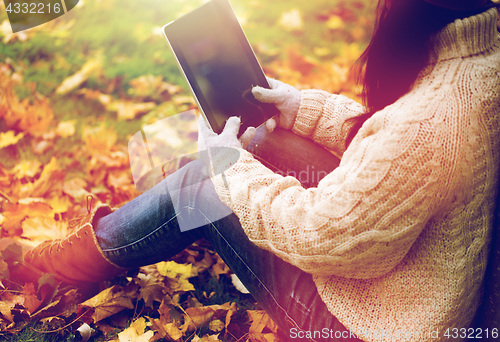 Image of close up of woman with tablet pc in autumn park