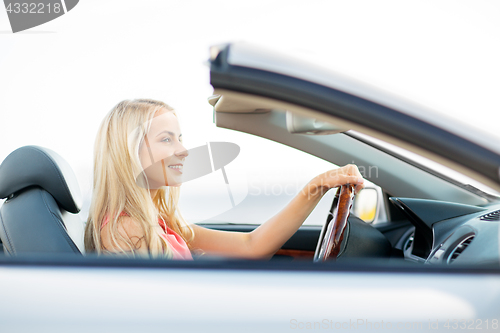 Image of happy young woman driving convertible car