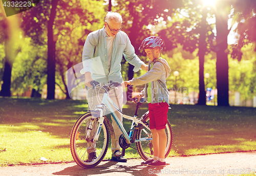 Image of grandfather and boy with bicycle at summer park