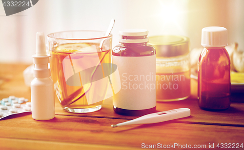 Image of drugs, thermometer, honey and cup of tea on wood