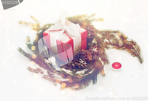 Image of christmas gift and fir wreath with cones on snow