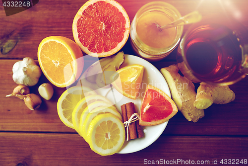 Image of ginger tea with honey, citrus and garlic on wood