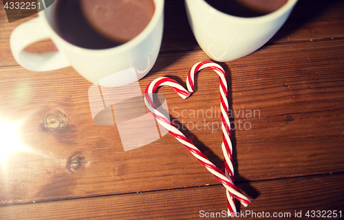 Image of christmas candy canes and cups on wooden table