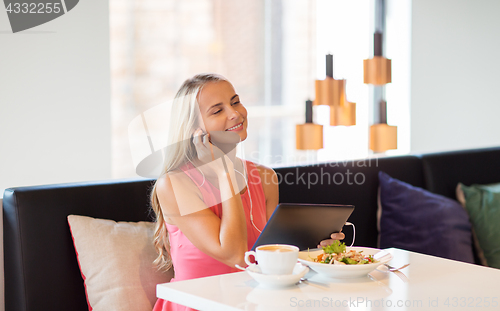 Image of happy young woman with tablet pc at restaurant