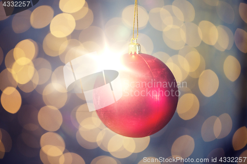 Image of close up of red christmas ball over golden lights