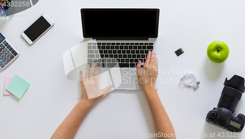 Image of woman with camera working on laptop at table