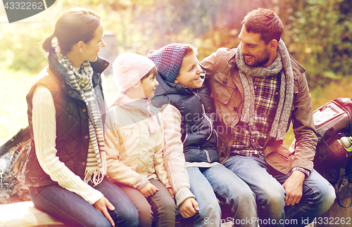 Image of happy family sitting on bench and talking at camp