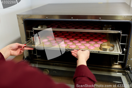 Image of chef with macarons on oven tray at confectionery